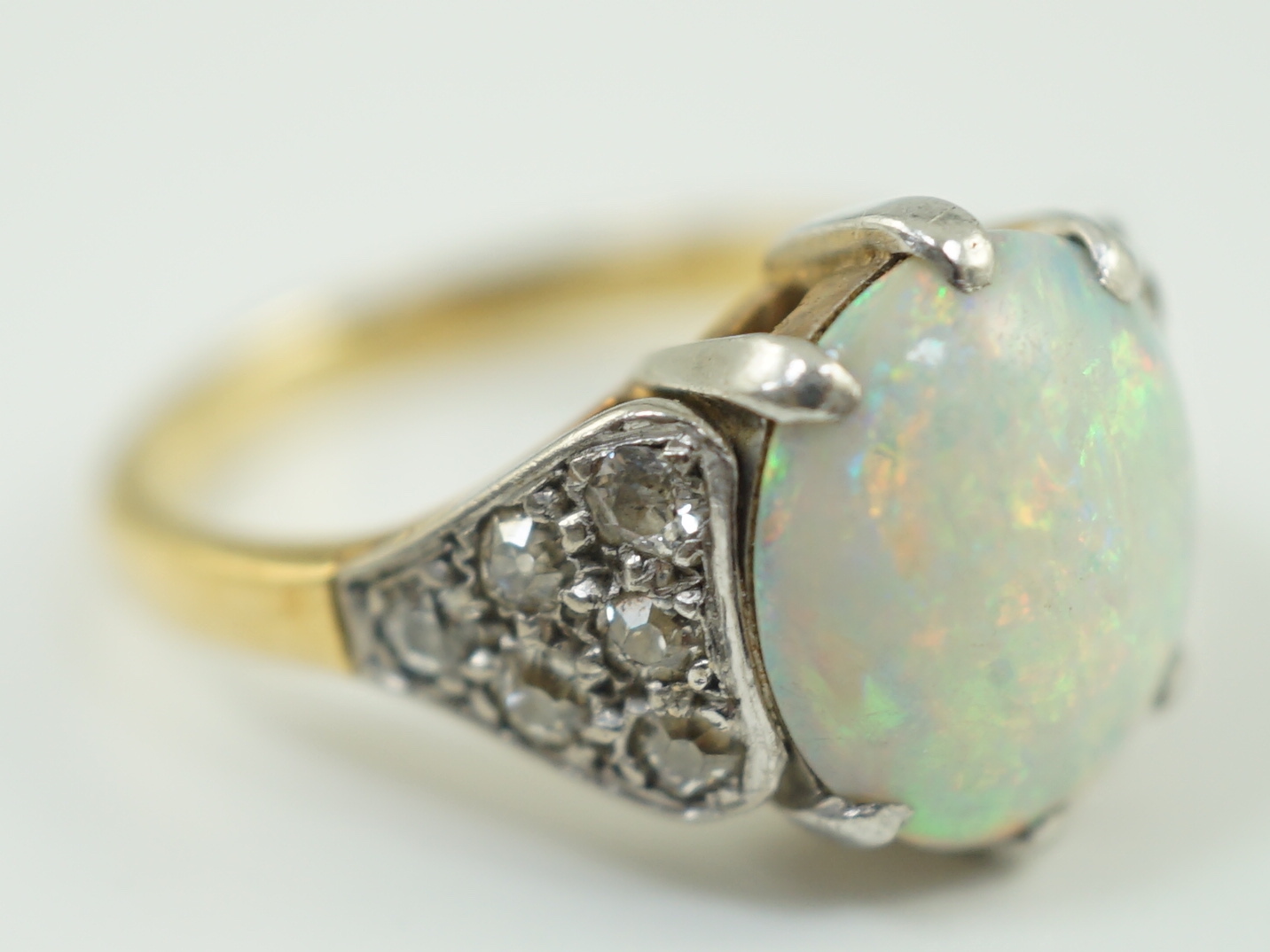 An 18ct gold and single stone white opal set ring, with twelve stone diamond set shoulders